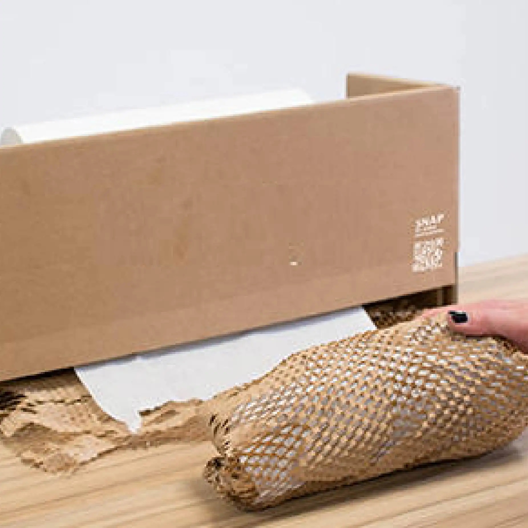 在淺灰色的背景下，用蜂巢包裝紙套裝包裝酒類產品的過程。